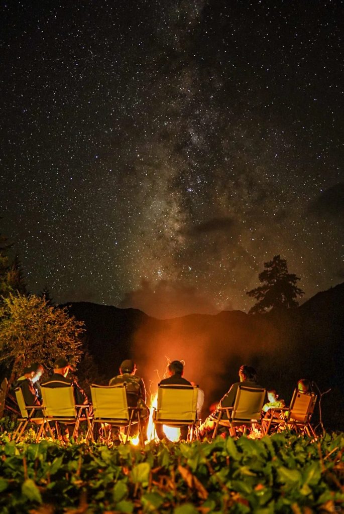 Gather around a bonfire at night, sharing stories under the mystical Tibetan sky.