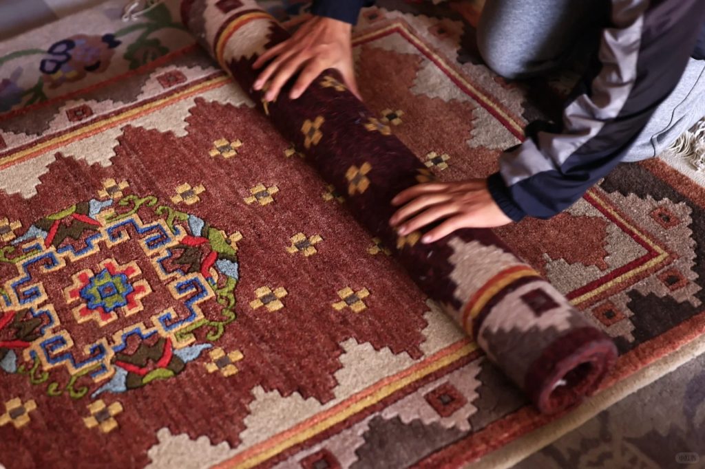 With practiced hands, the artisan carefully rolls the vibrant Tibetan carpet, its wool still carrying the scent of highland pastures.